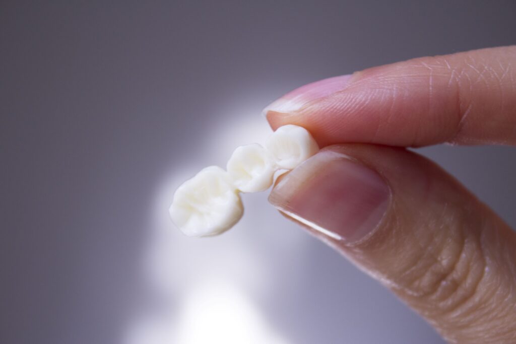 Closeup of fingers holding dental bridge